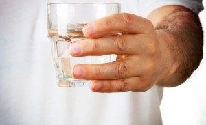 Man in white shirt hodling a glass of water